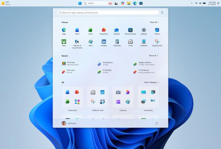Menú de inicio de Windows 11, con íconos de aplicaciones en colores brillantes, centrado en un fondo azul claro. Se muestran opciones de búsqueda y categorías.