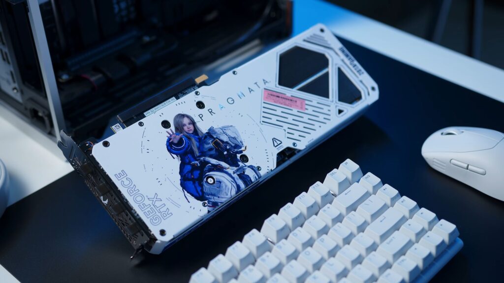Tarjeta gráfica RTX 5070 AMP PRAGMATA con diseño blanco y gráfico de un personaje, ubicada sobre un escritorio con teclado y ratón.