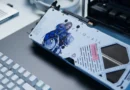 Tarjeta gráfica Zotac RTX 5070 AMP PRAGMATA con diseño artístico de personajes, colores blanco y azul, sobre una superficie oscura con un teclado.
