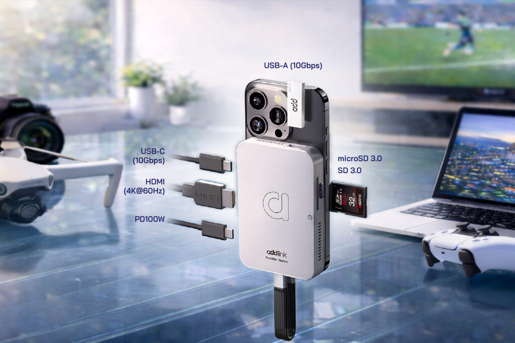Conector múltiple Addlink mostrando puertos USB-A, USB-C, HDMI y slot para microSD, con un dispositivo móvil y un fondo de gaming.