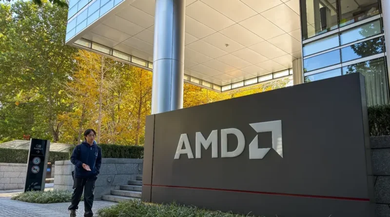 Edificio moderno de AMD con un cartel grande en primer plano, rodeado de vegetación y árboles con hojas amarillas en otoño.