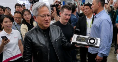 Jensen Huang sostiene una GPU GTX 1080 firmada, rodeado de personas en un evento, todos con sonrisas y cámaras.