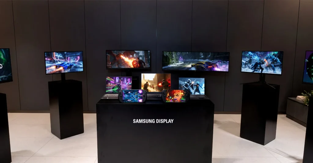 Varias pantallas de Samsung Display muestran contenido vibrante en un entorno minimalista con colores oscuros y una mesa central.