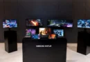 Varias pantallas de Samsung Display muestran contenido vibrante en un entorno minimalista con colores oscuros y una mesa central.