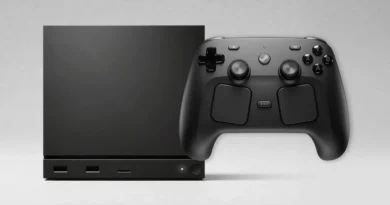 Consola negra rectangular junto a un controlador negro, ambos con diseño minimalista y botones visibles, sobre fondo gris claro.