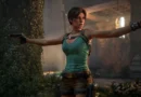 Lara Croft con dos pistolas, vestida con camiseta verde y pantalones cortos, en un entorno oscuro y misterioso lleno de vegetación.