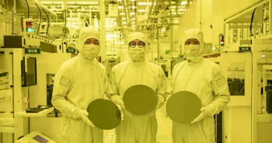 Tres trabajadores sostienen obleas de silicio en una sala de producción de semiconductores, destacando la demanda de chips para IA.