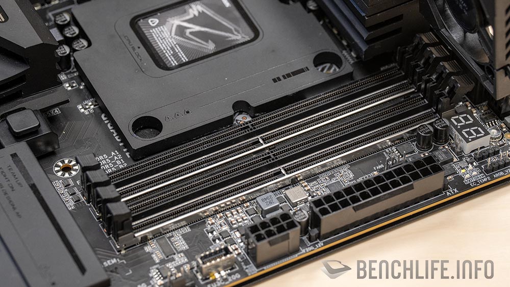 Placa base con diseño negro y detalles metálicos, tres conectores EPS para alimentación y ranuras de memoria RAM visibles.