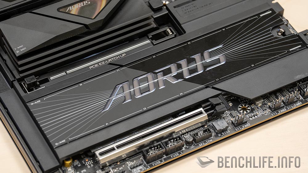 Placa base AORUS con diseño elegante en negro y plata, destacando el conector EPS triple y ranuras para tarjetas gráficas.
