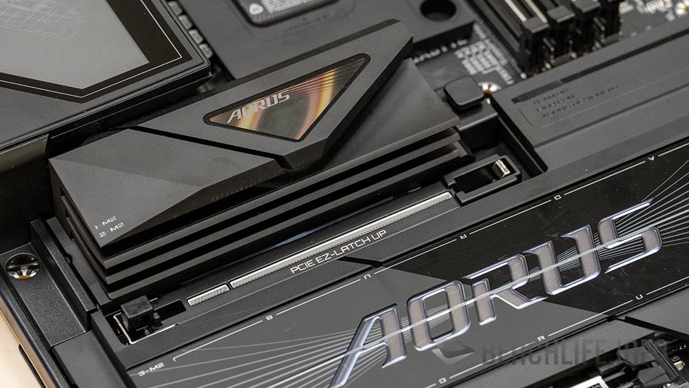 Placa base AORUS con disipador negro, destaca el conector EPS triple y diseño moderno con detalles plateados y líneas futuristas.