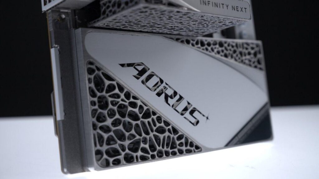 Tarjeta gráfica AORUS con diseño plateado y detalles en textura negra, destacando el logotipo "AORUS" en un fondo oscuro.